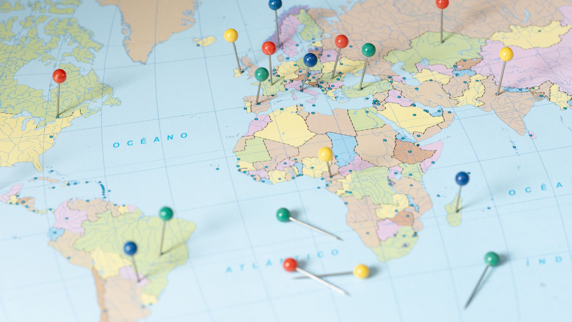A world map featuring red, green, blue, and yellow pushpins placed across various countries and continents.