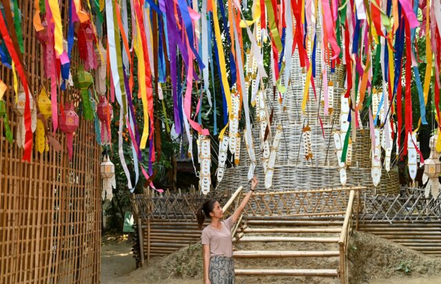 Woman amidst colourful hanging ribbons