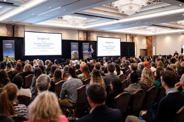 Large audience of teachers attending an Inspired careers conference, listening to a keynote presentation about the Global Exchange Programme in a conference hall.
