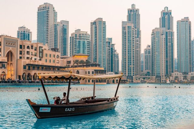 A traditional wooden abra boat floating on the water with modern skyscrapers in the background, illustrating what moving to the UAE as a teacher can look like.