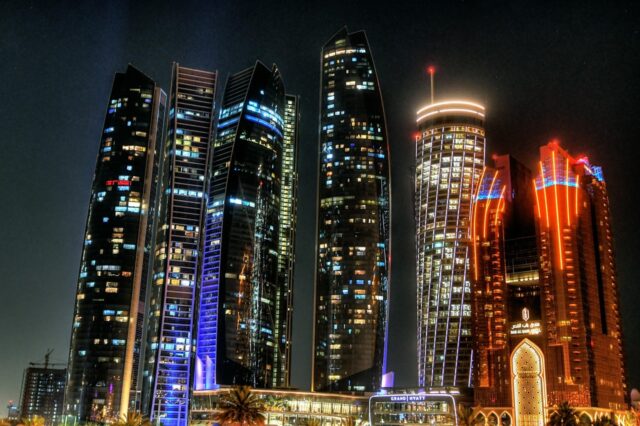 Illuminated city skyscrapers and futuristic high-rise buildings at night.