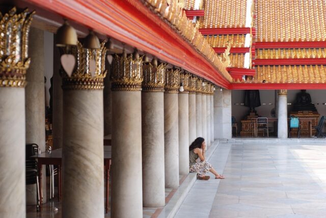 Woman sitting on steps at a traditional Thai temple in Bangkok