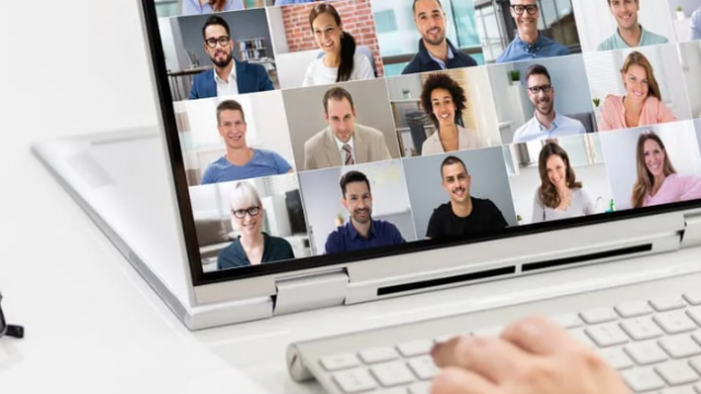 Person participating in a virtual meeting on a laptop, with multiple video call participants shown in a grid layout on screen