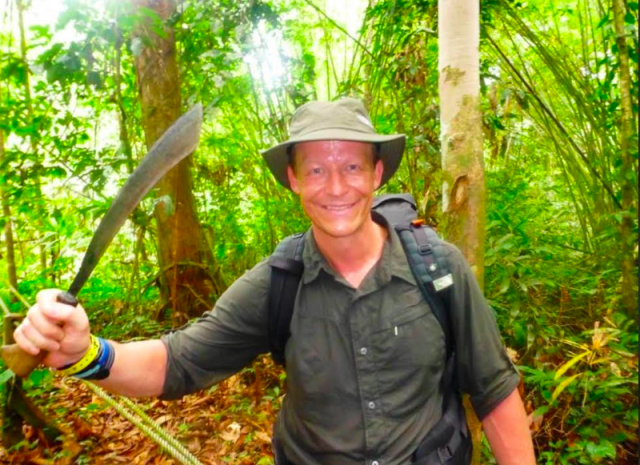 Steve Hill, an adventurous educator, holding a machete in a lush Amazon Jungle, showcasing his participation in the Jungle Ultra race.